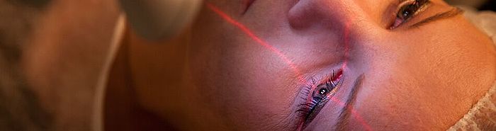 Augenlasern im Augenzentrum in München Frau lässt sich die Augen Lasern - der Laser markiert das linke Auge mit einem Fadenkreuz.